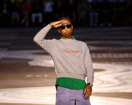 Pharrell Williams, wearing sunglasses and a grey sweatshirt, salutes the audience after the show
