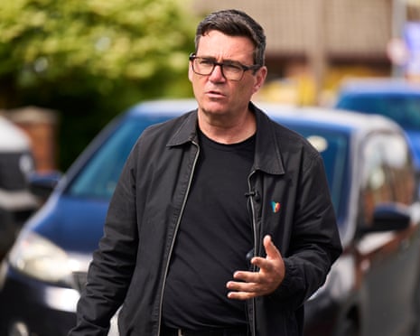 Andy Burnham walks outdoors, gesturing as he speaks