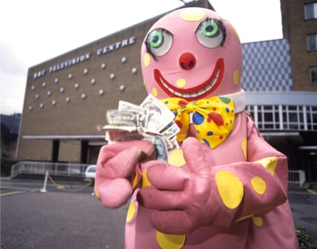 Mr Blobby clasps a handful of bank notes in front of BBC Television Centre.
