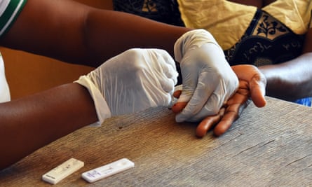 An African health worker pricking the finger of a child for a blood test