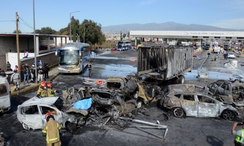 Rescuers look through bunt-out cars after a truck crashed into a toll booth in Mexico, killing at least 19 people