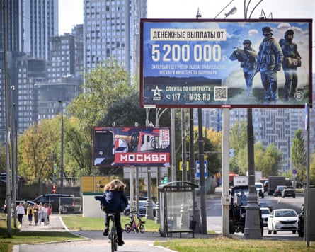 A cyclist passes a billboard