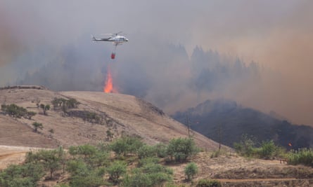 A helicopter carries water to drop on the fire near the village of Gáldar