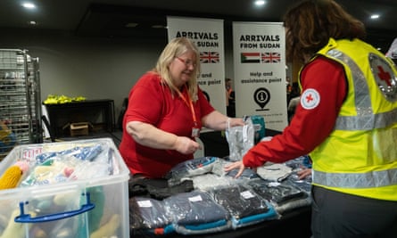 Voluntários e funcionários da Cruz Vermelha Britânica prestam apoio às pessoas que chegam do Sudão ao Reino Unido. Voluntários de resposta a emergências foram enviados ao Aeroporto de Stansted para ajudar as pessoas que foram evacuadas do país após a eclosão do conflito. Corinne, voluntária da Cruz Vermelha Britânica.