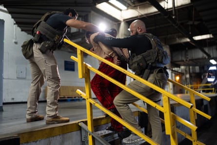 Homeland Security officers escort a handcuffed man to a processing facility.