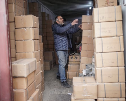 A man between two piles of cardboard boxes that reach head height.