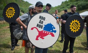 A white nationalist holds a shield that reads ‘Enough is enough’ at a private campground in Whitesburg