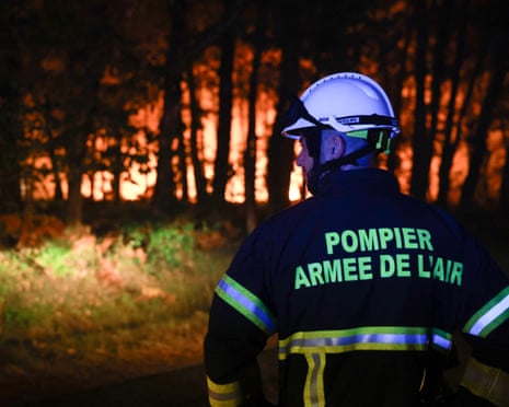 A firefighter with the French Air Force looks on as a wildfire rages through the Landes forest in Luglon, southwestern France.