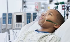 A black boy wearing oxygen mask in hospital bed