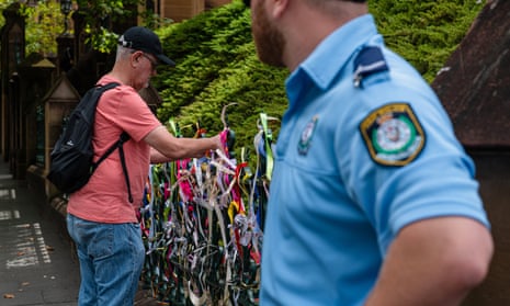 A man ties a ribbon to the fence of St Mary’s Cathedral during the pontifical requiem mass for Cardinal George Pell yesterday.