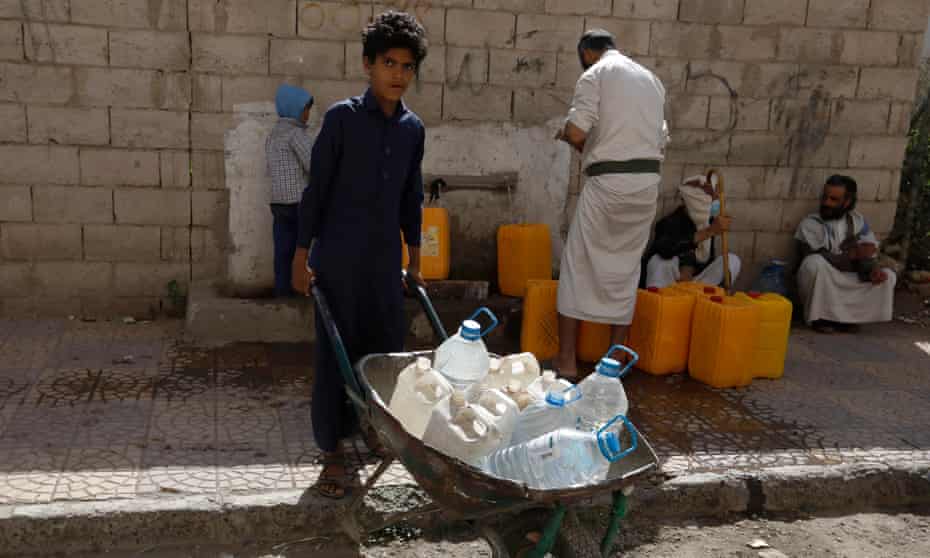 People collect drinking water from a donated water pipe on the roadside in Yemen’s capital, Sana’a.
