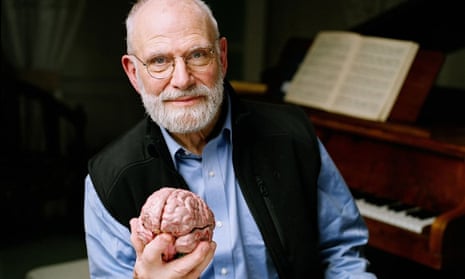 In this 2007 photo provided by the BBC, Neurologist Oliver Sacks poses at a piano while holding a model of a brain at the Chemistry Auditorium, University College London in London.