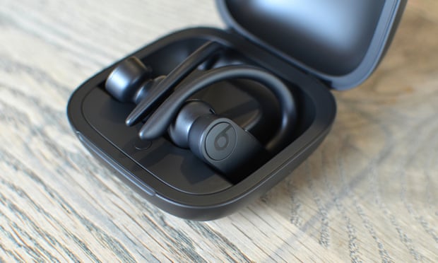The PowerBeats Pro clipped into their magnetic charging case on a desk.