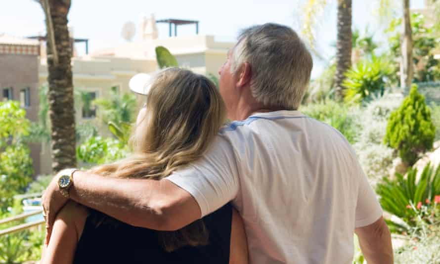 A newly retired couple standing on the balcony of their new home in Spain
