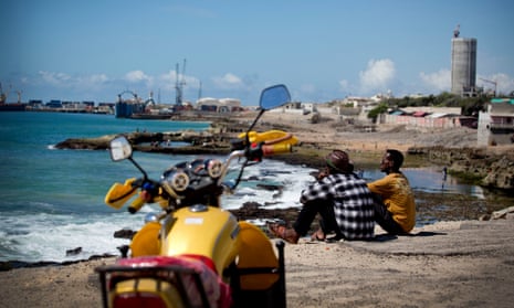 Two men sit looking out over the harbour and port of the Somali capital, Mogadishu.