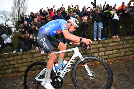 Mathieu van der Poel cycling on a cobblestone road.