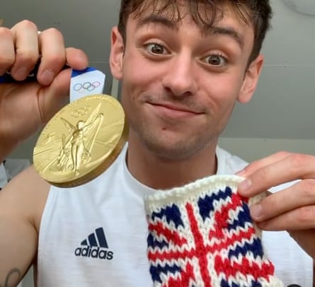 Team GB’s Tom Daley holds up his gold medal and the knitted holder.