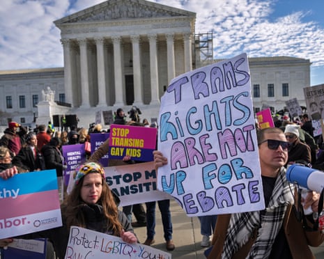 people hold signs in front of white building