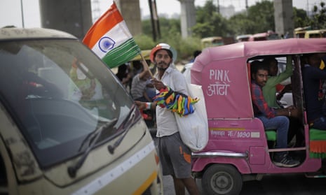 A street hawker sells flags and other merchandise at an intersection in Delhi