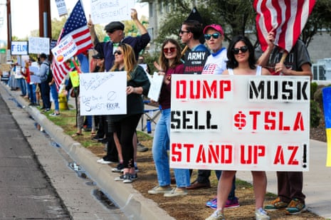 people hold signs while standing along a road