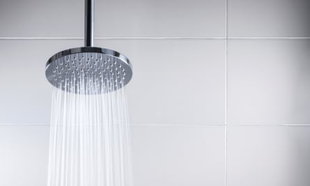 Water running from modern rain shower head in tile shower