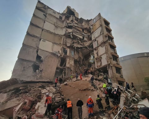 Ring of rescue workers beneath shell of destroyed building