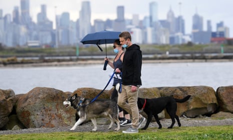People wearing face masks walk their dogs in Melbourne on Sunday as Victoria recorded 92 new Covid cases.