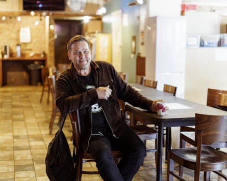 A smiling man in black sitting at a dining table