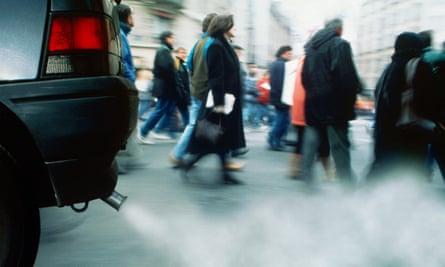 People walk through car exhaust fumes