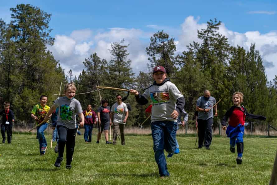 Des enfants courent vers le but lors d'une partie de double ballon.  Frank Old Horn, membre de la tribu CSKT, a déclaré qu'il existe de nombreuses histoires d'origine différentes sur le jeu, mais beaucoup disent que les guerriers jouaient au double ballon pour se préparer au combat.