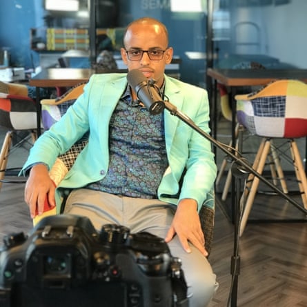 Abdisamad Xaliye sits at a microphone looking at a camera.