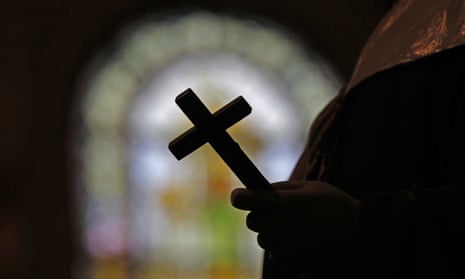 silhouette of person holding a cross against a stained glass window
