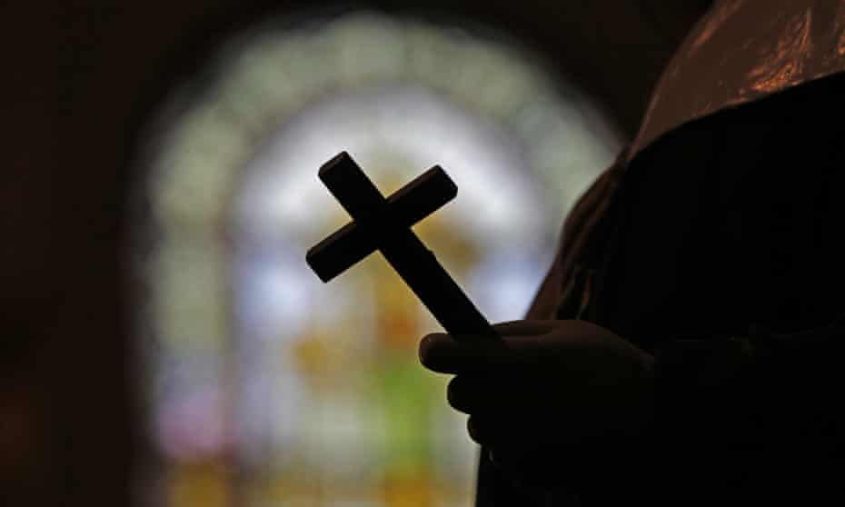 A crucifix and a stained glass window inside a Catholic church