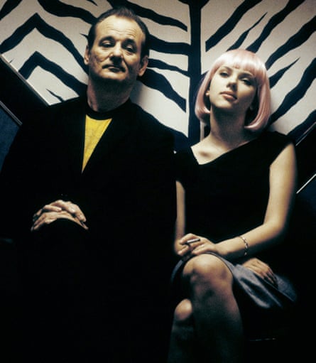 A man in a dark suit and a yellow T-shirt and a blond girl in a short black dress