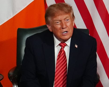 President Trump speaks while seated in front of Irish and American flags