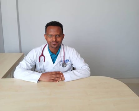 Dr Abraha Gebreegziabher wearing a white coat, sitting behind a desk