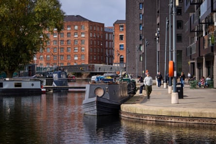 Narrowboats moor on New Islington Marina in Ancoats, Manchester, beside a paved waterfront