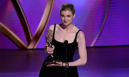 woman wearing black dress holds gold statue