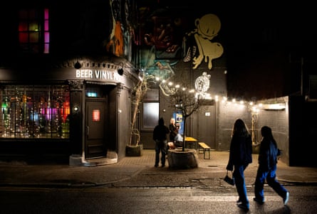 A dark night in Birmingham with the silhouettes of two young people about to enter a pub called Beer Vinyl