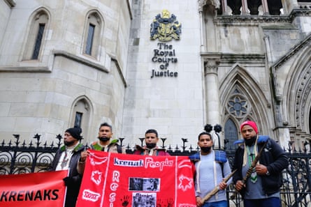 Members of the Brazilian Krenak community hold a banner outside the court of justice in London