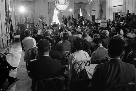 An audience of several rows of people watch Johnson give a speech at a lectern