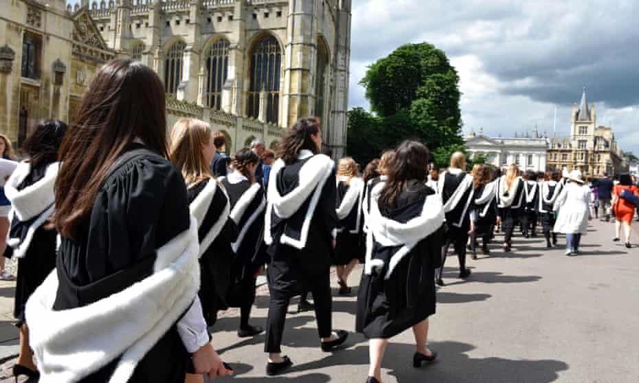Students in graduation gowns walking past Kings College in Cambridge