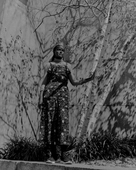 A woman covered in tree shadows stands for a potrait