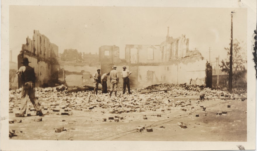 Black Tulsa residents stand in front of a leveled building in Greenwood after the violence subsided.