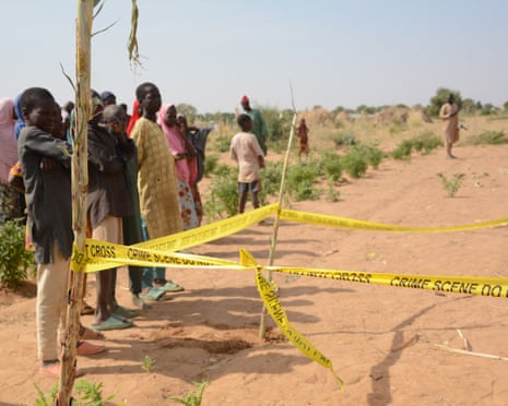 People stand behind crime scene tape at the site of an airstrike.