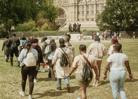 People walking across a grassy area outside an old building with the organisation Ebony Bonds
