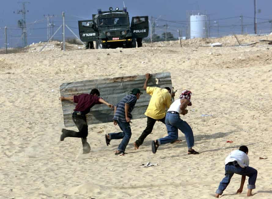 Des jeunes palestiniens se mettent à l'abri de la police derrière une tôle ondulée en 2000