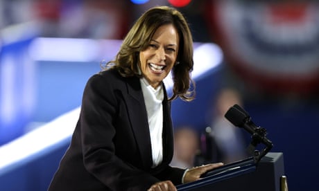 Woman in blazer laughs at lectern.