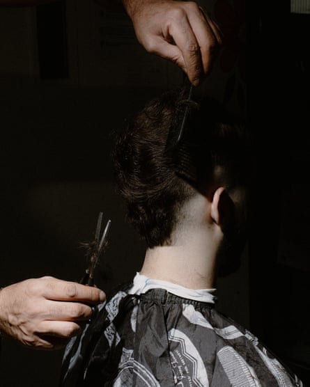 A boy has his hair cut in the dark