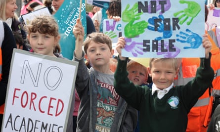 Children hold up signs protesting against converting schools to academies